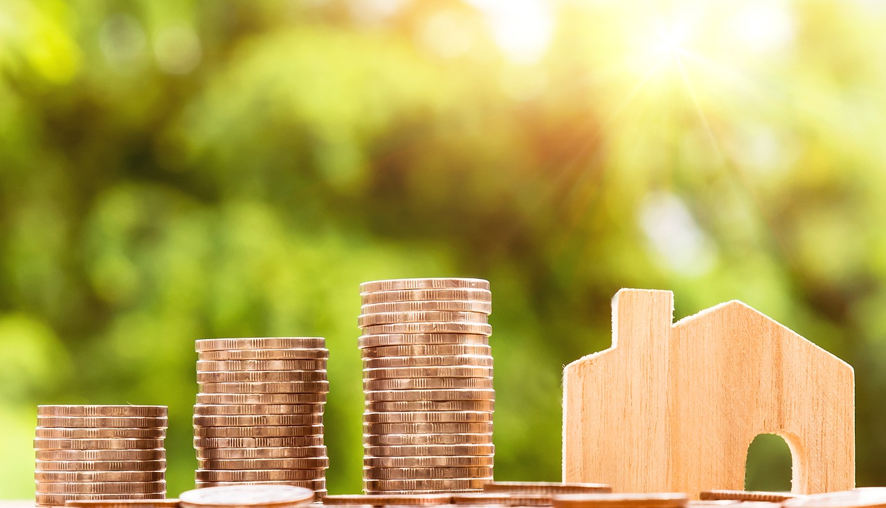 pile of coins along side a little wooden house